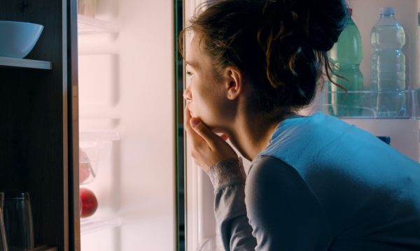 Woman Looking Into a Fridge Late At Night for the Article How to Curb After Dinner Cravings