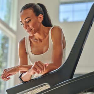 Person pausing mid-workout on treadmill, showing workout fatigue and recovery awareness.