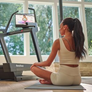 The X24 Incline trainer treadmill in a home setting with scenic background, highlighting NordicTrack’s flagship treadmill design and premium build